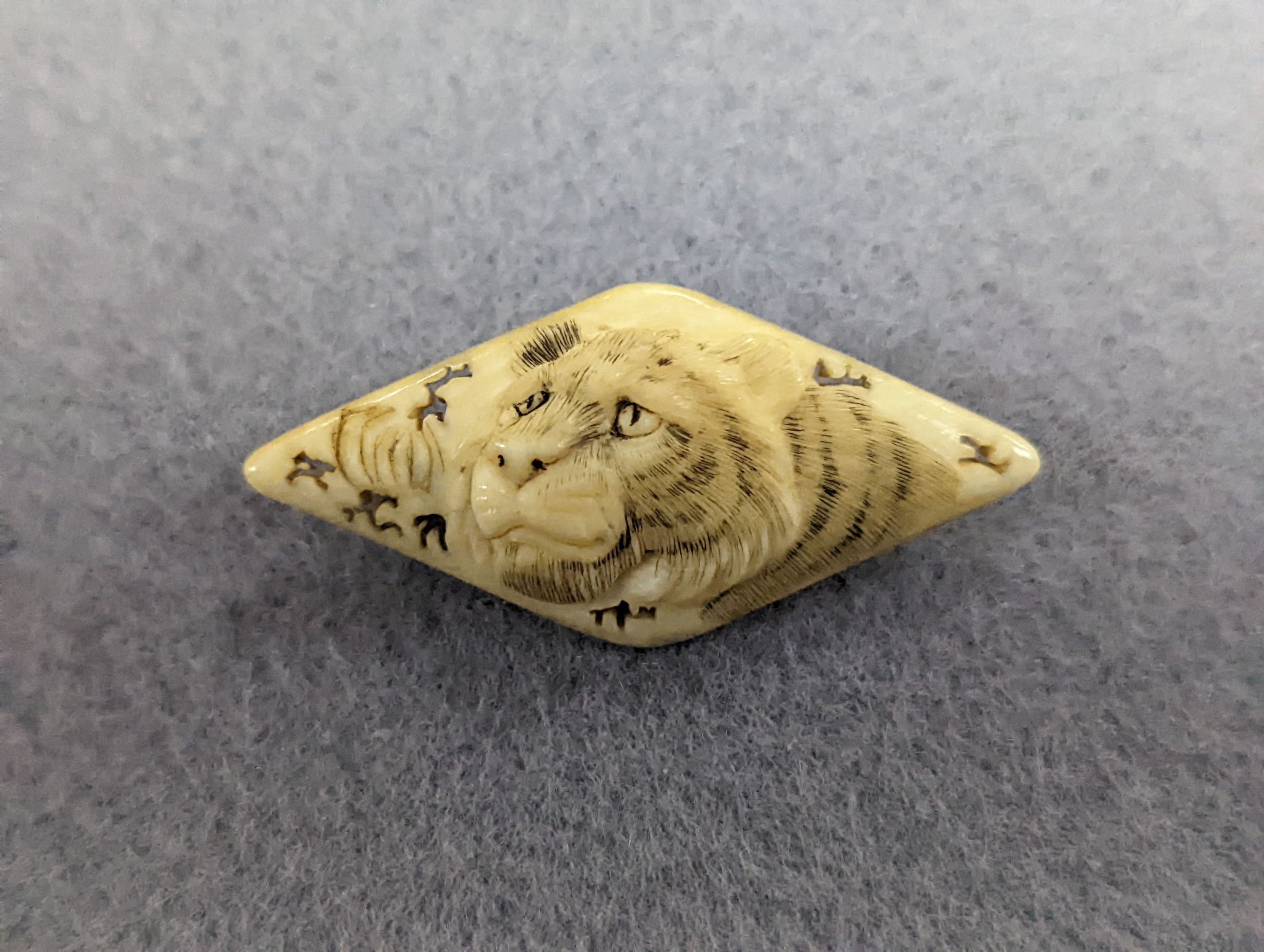 A pair of 19th century ivory balm pots, 3.75cm., a smallDieppe triptych figure, 6.5cm. a Meiji tiger brooch and a Dutch page marker.